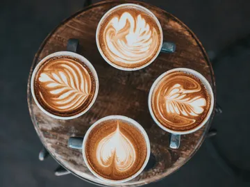 Four coffee cups lie on a wooden table.