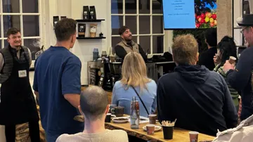 People listen to a speaker in a café environment.