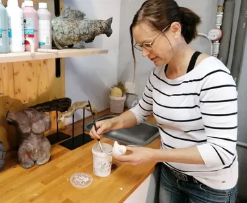 Frau malt eine Skulptur in einem kreativen Atelier.