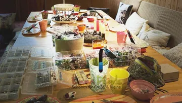 Tisch mit Bastelmaterialien, sortiert und vorbereitet zum Arbeiten.