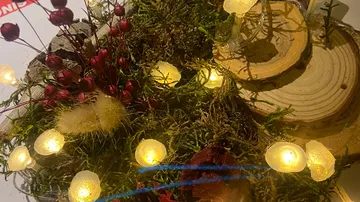 Dekorative Holzscheiben, Moos, Blüten und Lichtakzente.