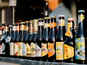 Bierflaschen stehen nebeneinander auf einem Tisch im Freien.