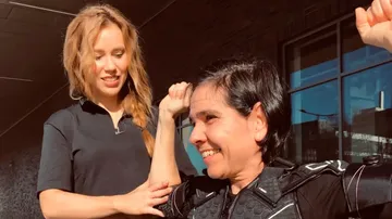 Zwei Frauen interagieren, eine hilft der anderen beim Training.