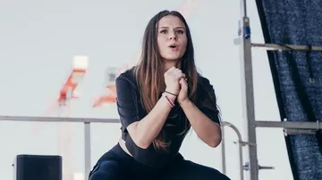 Young woman performs energetically on an outdoor stage.