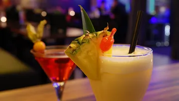 Zwei Cocktails stehen auf einem Tisch in einer Bar.