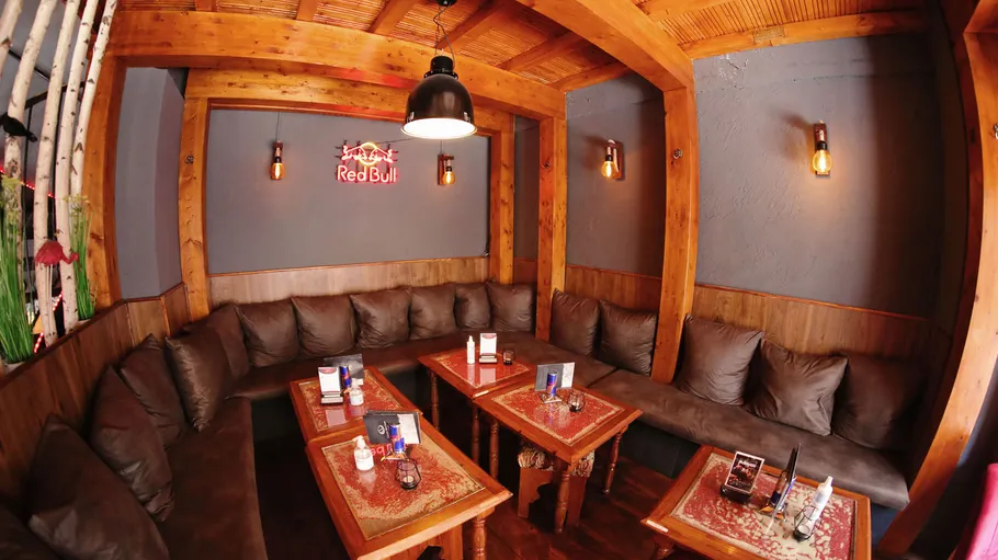 Wooden benches sit around a table in a cozy space.