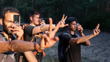 Vier Männer fotografieren im Wald mit Kameras.