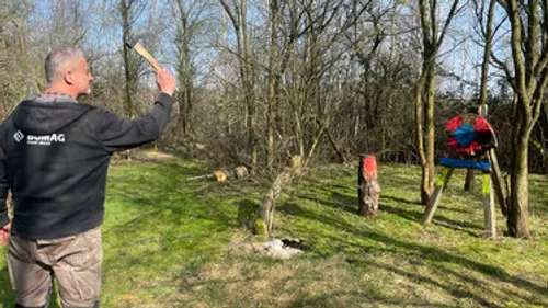 Mann wirft Holzstück auf Ziel im Wald.