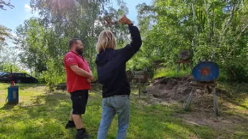 Person wirft einen Gegenstand auf Zielscheiben im Freien.