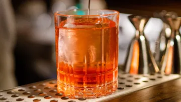 Ein Glas Cocktail wird auf einer Arbeitsfläche gerührt.