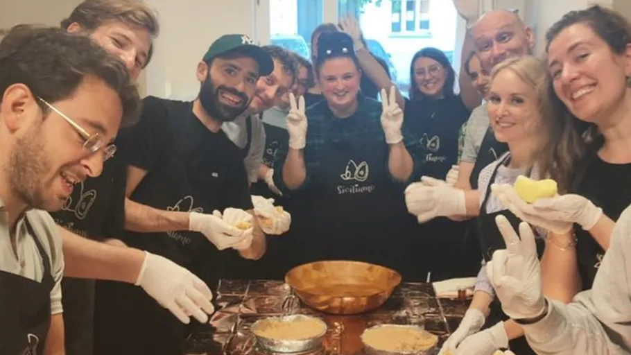 Group of people prepare food together in a kitchen.