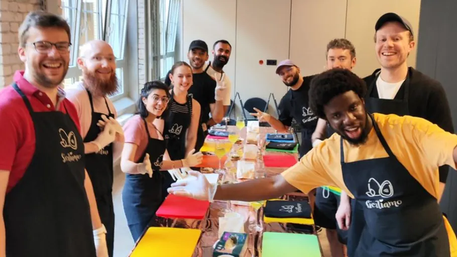 Group laughs and poses in front of colorful painting supplies.