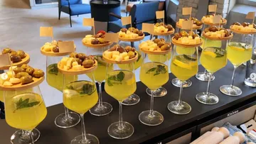 Glasses with colorful cocktails topped with fruit and olives.
