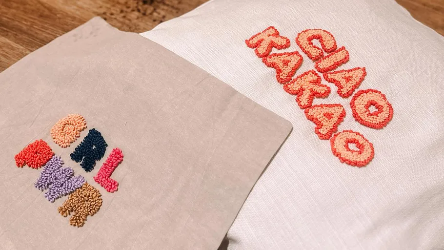 Two cushions with colorful embroidery patterns on fabric.