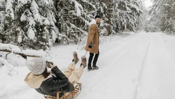 Schlitten fährt auf schneebedecktem Weg, Menschen genießen Winterspaß.