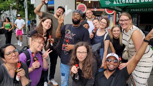 Group of people smiling with drinks in street.