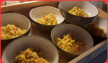 Six bowls of yellow rice dish on a tray.