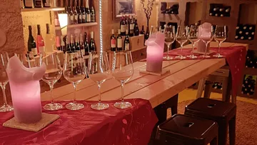 White wine glasses are placed on a table, lit by candles.