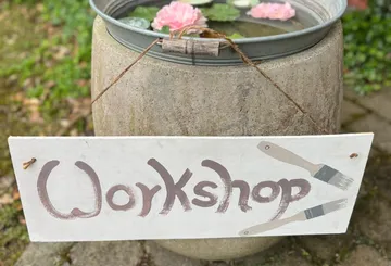 Ein Schilder mit "Workshop" hängt über einem Wasserbehälter.