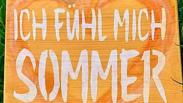 Holzschild mit Text zeigt sommerliches Gefühl im Freien.