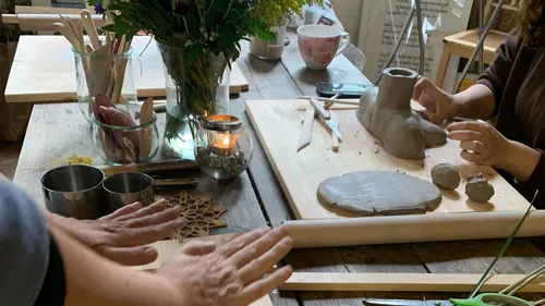 Pottery is worked while plants and candles decorate.