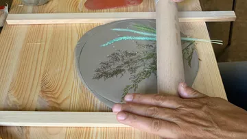 Clay plate is worked with a rolling pin, herbal print.