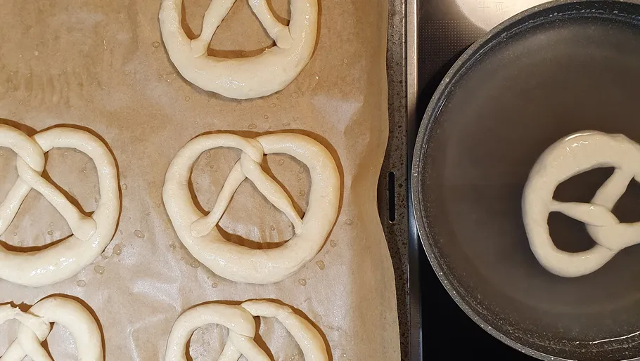 Geformte Brezenteiglinge auf einem Blech mit Backpapier