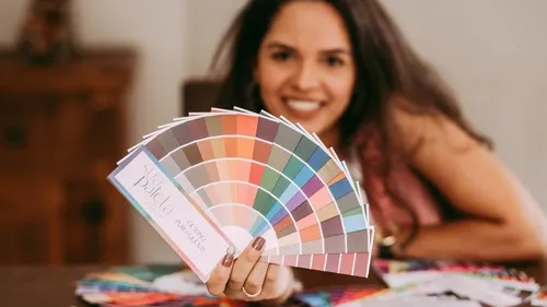 Woman holding color samples, smiles happily.