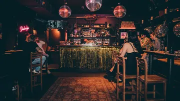 Bar mit Disco-Kugeln, Gäste sitzen entspannt, gedämpftes Licht.