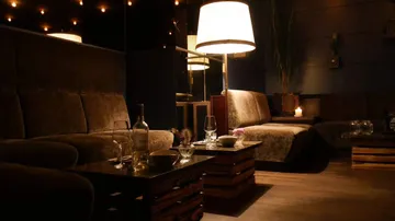 Comfortable seats, table with glasses, relaxed atmosphere in the dark.