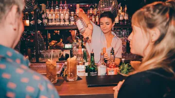 Bartender stands behind the bar and makes cocktails for guests.