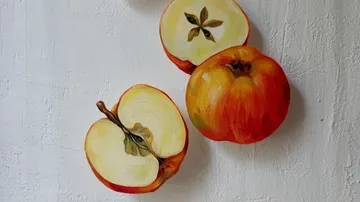 Äpfel liegen auf einer weißen Fläche, teilweise geschnitten.