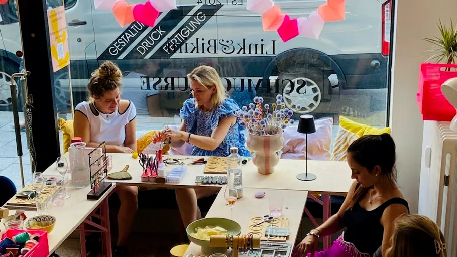 Three women are tinkering with tables in a colorful room.