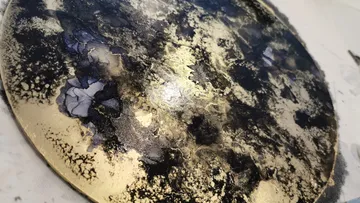 Round plate, lacquered, with gold and black patterns.