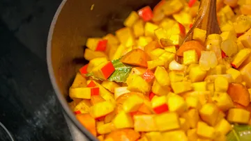 Gemüsewürfel werden in einem Topf gekocht.