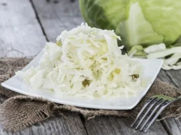 Sliced cheese on a plate surrounded by fresh vegetables.