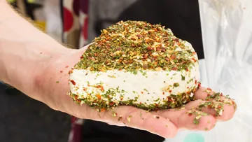 Käse mit Gewürzen wird von Hand gehalten, im Freien.