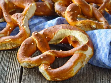Pretzels lie on a blue cloth, arranged in a rustic way.