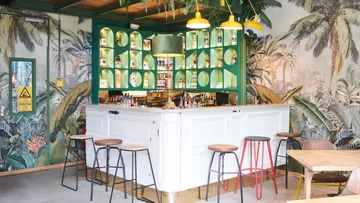 Bright bar with plant patterns and colorful stools in the background.