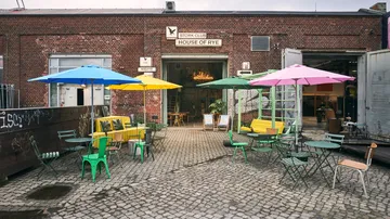 Colourful outdoor tables and chairs in front of an entrance.