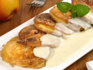 Fried apple rings with cream sauce on a plate.