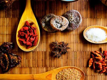 Spices and dried fruits lie on a wooden board.