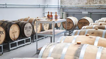 Barrel storage with wooden barrels, bottles on a table.