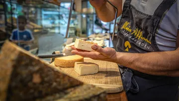 Käsehändler schneidet Käse im Feinkostladen.