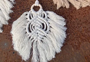 Woven decorative piece hangs over red metal surface