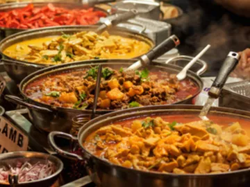 Three pots of steaming dishes at a market.