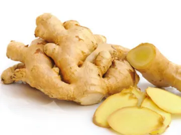 Ginger root lies uncut with sliced slices next to it.