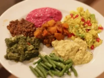 Verschiedene indische Gerichte auf einem weißen Teller arrangiert.