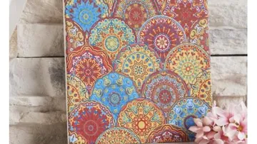 Colourful wall decoration with geometric patterns against a stone wall.
