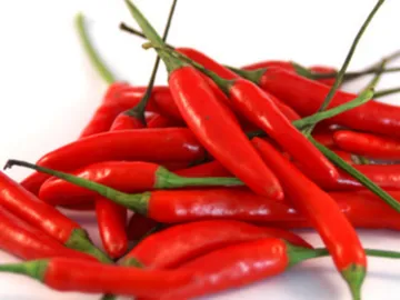 Rote Chilis liegen übereinander auf einem weißen Hintergrund.